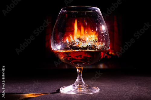 Close-up on a glass of brandy in the dark on the background of the fireplace