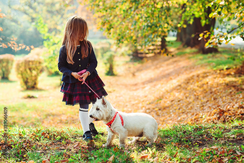 Happy girl walking with dog on a leash in autumn. Best friends, friendship.