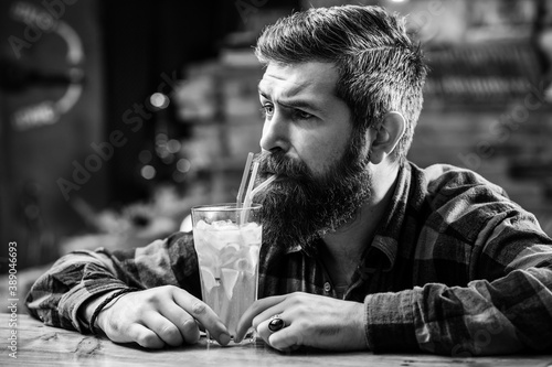 Bearded man drinks cocktail. Handsome barber resting at pub. Bearded brutal hipster thinking. Alcoholic fresh cocktail.