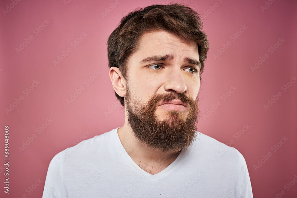 Fototapeta premium bearded man in white t-shirt emotions displeased facial expression studio pink background
