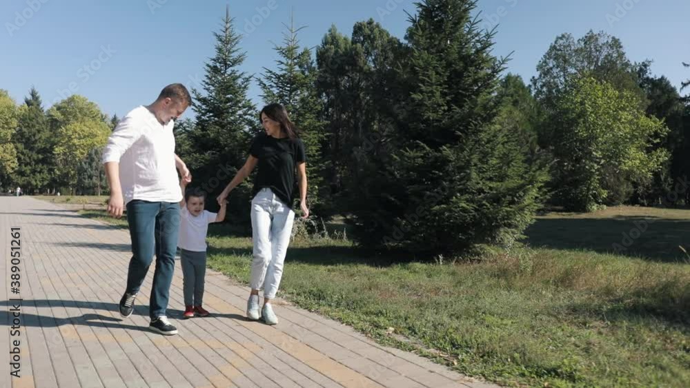 Walking An Idyllic Young Caucasian Family With A Little Boy In The Park.Family Park For Walking Walking An Idyllic Young Caucasian Family With A Little Boy In The Park.Family Park For Walking