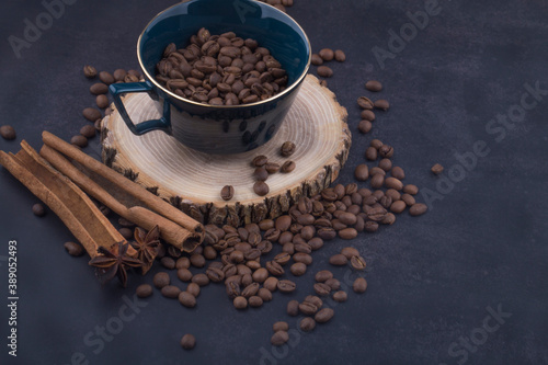 Cup of coffee with coffee beans and cinnamon sticks.