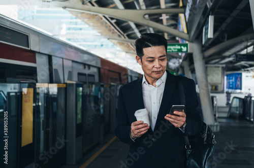 Serious business man using smart phone and waiting at train station