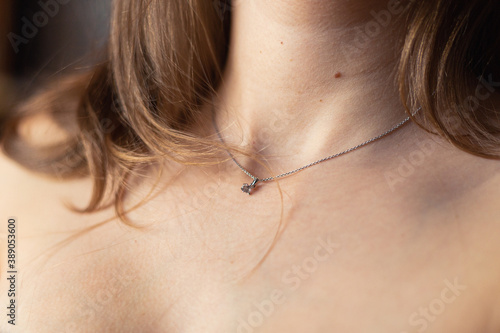Nude blonde woman's neck with silver necklace close-up.