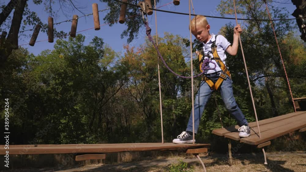 Little boy passing the cable route high among trees, extreme sport in adventure park. Little boy passing the cable route high among trees, extreme sport in adventure park.