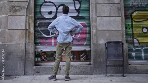 Young business man closing a small local store door during the coronavirus crisis. Shops in a European city being closed