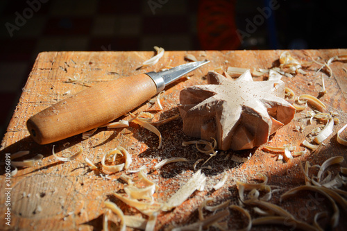 Wood carving from linden wood. Work table in woodworking workshop with carving knife. Woodworking process. 