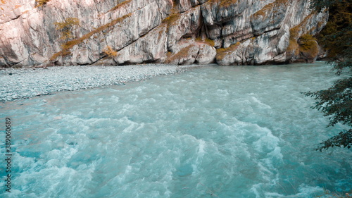 A turquoise river flows along the cliff. The mountain river flows rapidly.