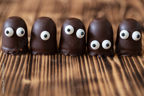 Geist oder Gespenst oder Alien aus Schaumkuss mit Augen aus Zucker auf einem braunen Tisch aus Holz photo