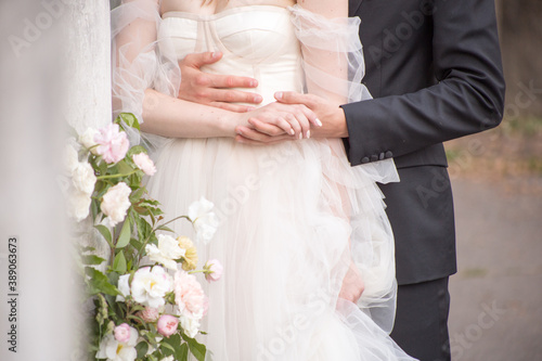 the groom stands behind the bride, hugs and holds her hand