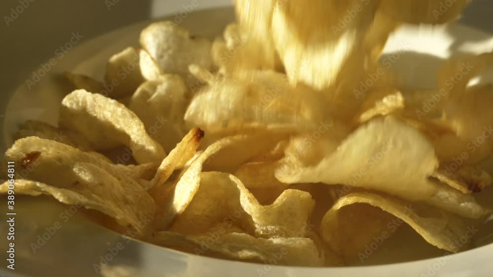 Potato Chips fall into white plate in slow motion close up Potato Chips fall into white plate in slow motion close up
