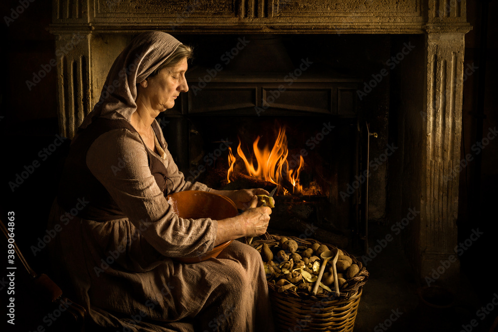 Woman peeling potatoes at fireplace