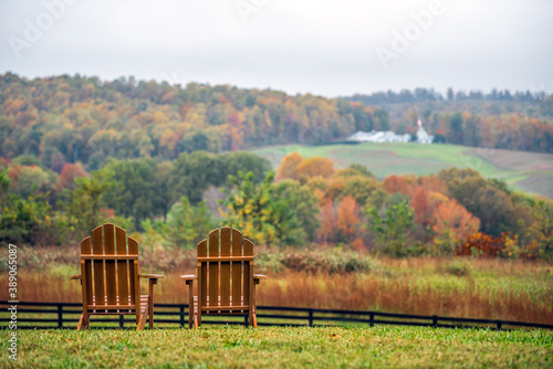 Empty wooden chairs in autumn fall foliage season countryside at Charlottesville winery vineyard in blue ridge mountains of Virginia with cloudy sky day