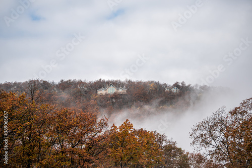 Wintergreen, USA ski resort town in Blue Ridge mountains in autumn fall with mist fog clouds and orange foliage on trees mountain peak