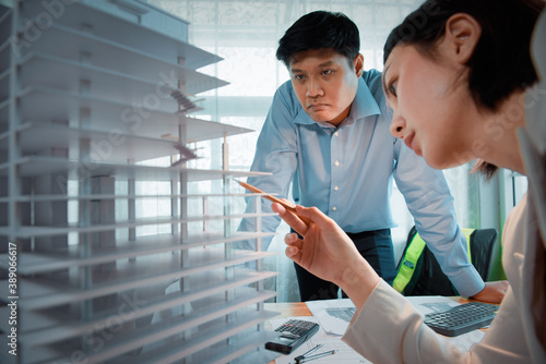 Two people Male and Female Asian architects discussing about concept of building design and construction project of community mall in Tall buildings. photo