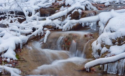 small river rushing over autumn mountain canyon covered by a snow, winter mountain scene © Yuriy Kulik