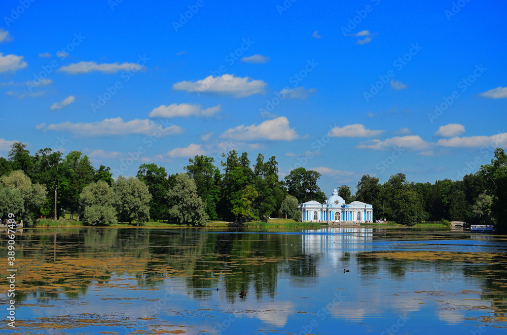 Fototapeta premium Scenery. View of the Grotto Pavilion in the mezeum of the Tsarskoe Selo nature reserve with reflection in the pond. Horizontal orientation. Russia, Saint Petersburg, 08/17/2020