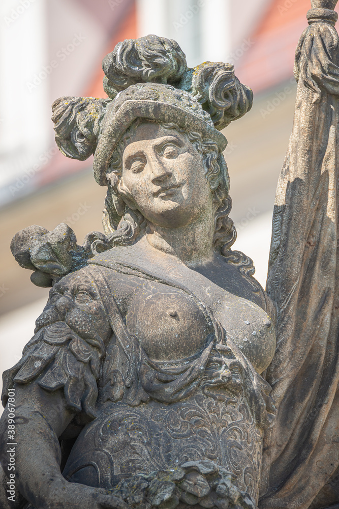 Old statue of a sensual woman warrior, Amazonian, as defender with flag at the Neumarkt in historical and shopping downtown of Dresden, Germany, details, closeup.