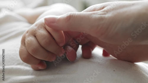 Macro of hands of young unrecognizable woman and charming small hand on toddler holing his mother hand