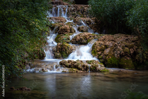 Small waterfall among the vegetation pouring water into a lake  Orbaneja del Castillo  Burgos  Spain