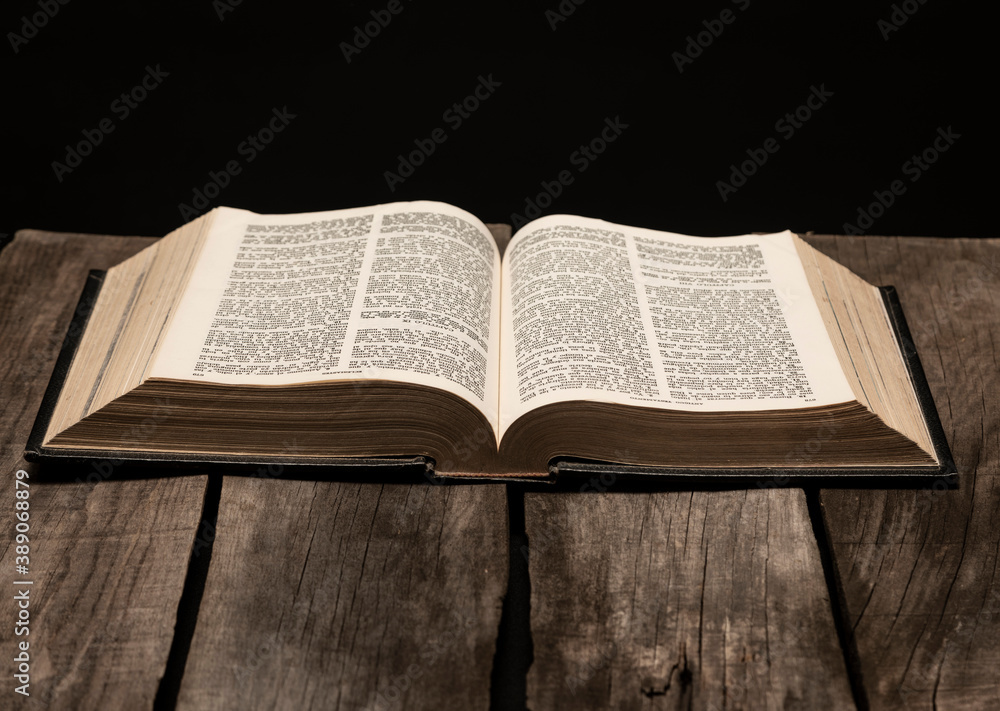 Holy bible open on rustic wooden table in dark night. Holy bible open on rustic wooden table in dark night.