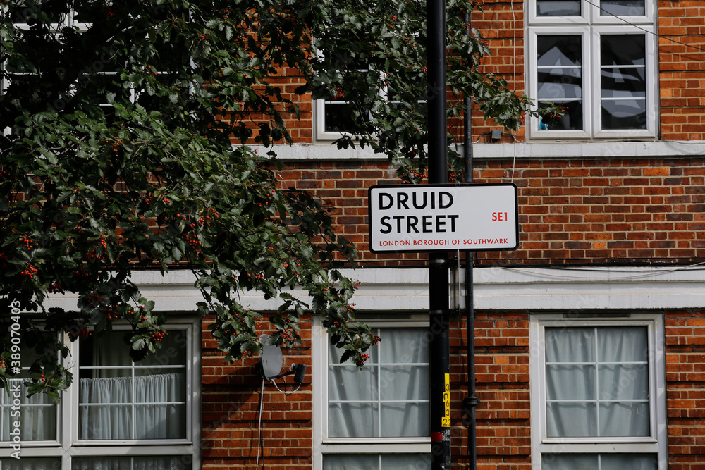 Obraz premium A traditional London location sign named Druid street is seen in front of an apartment building in Southwark borough, London, United Kingdom.