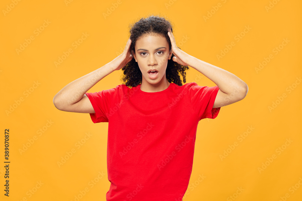 Woman with black curly hair holds her hand on her head red t-shirt Woman with black curly hair holds her hand on her head red t-shirt