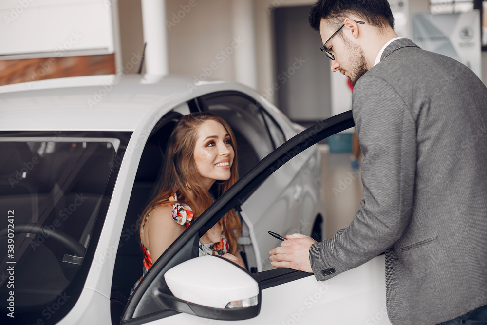 Lady in a car salon. Woman buying the car. Elegant woman in a dress. Assistent with a client Lady in a car salon. Woman buying the car. Elegant woman in a dress. Assistent with a client