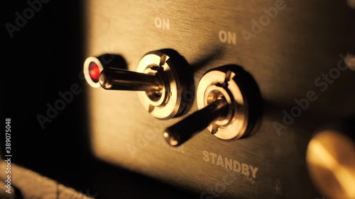 Turning on a guitar amplifier power switch slow motion macro closeup
