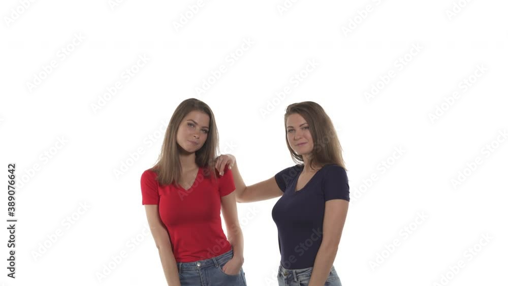 Portrait of friendly Caucasian twin sisters giving high five. Woman in black t-shirt holding hand on her sister's shoulder. Isolated on white background Portrait of friendly Caucasian twin sisters giving high five. Woman in black t-shirt holding hand on her sister's shoulder. Isolated on white background
