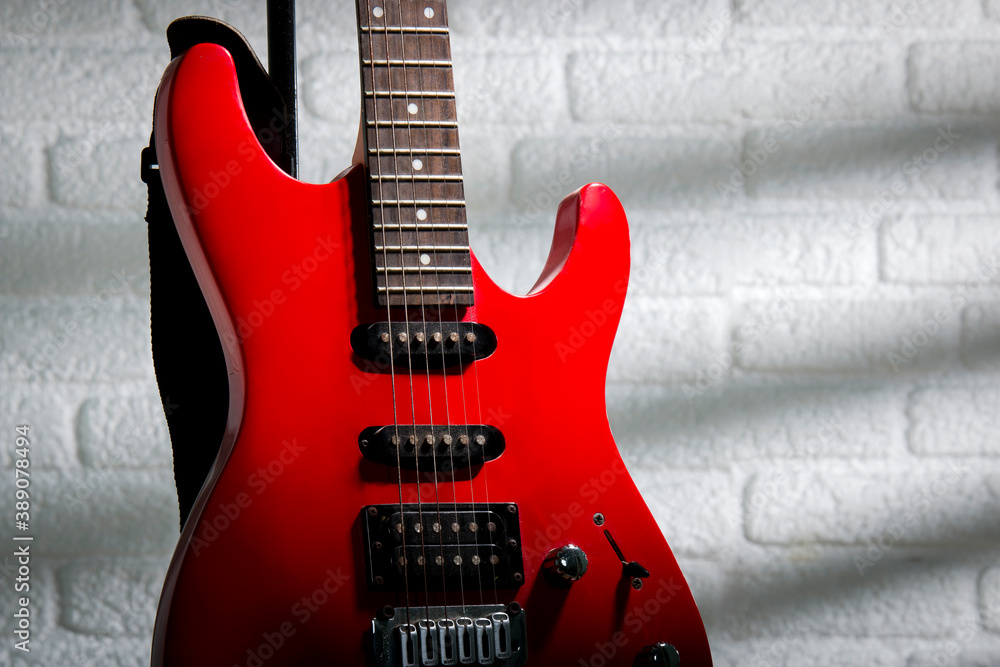 Red electric guitar in front of a white wall