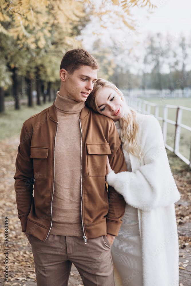 Beautiful young couple in autumn walks with dogs, pomeranian, in the park Beautiful young couple in autumn walks with dogs, pomeranian, in the park