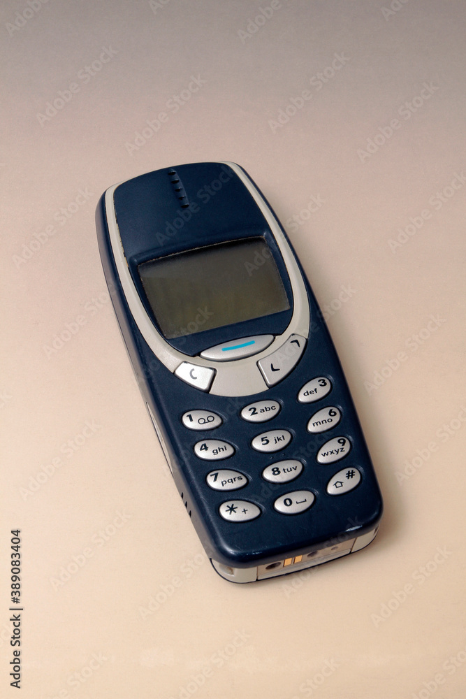 Close up of and old analogue mobile cell phone. Old fashioned black mobile phone isolated on white background. Vintage mobile phone.