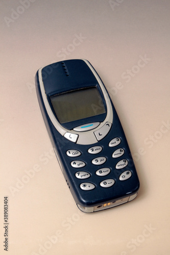 Close up of and old analogue mobile cell phone. Old fashioned black mobile phone isolated on white background. Vintage mobile phone.