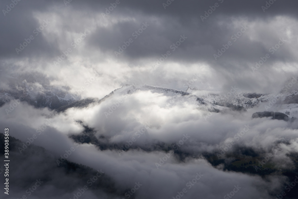 Forested mountain slope in low lying cloud with the evergreen conifers shrouded in mist in a scenic landscape view and snow in the dolomites Forested mountain slope in low lying cloud with the evergreen conifers shrouded in mist in a scenic landscape view and snow in the dolomites