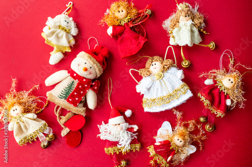 Handmade Christmas decorations. Angels, snowmen, santa. Red background. View from above.