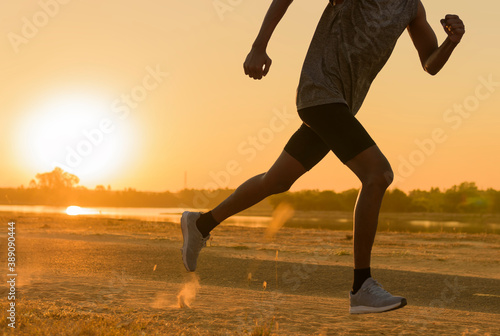 Runner feet running on road closeup on shoe. man fitness sunrise jog workout welness concept.