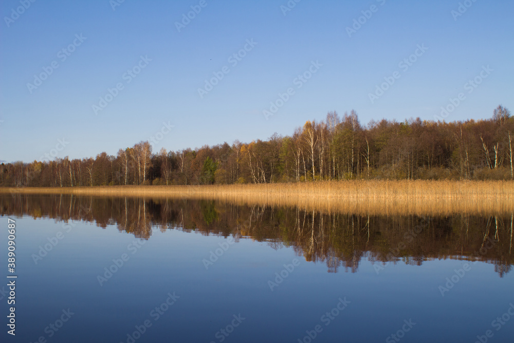 The autumn forest is reflected in the lake water.The concept of a private holiday. Horizontal orientation