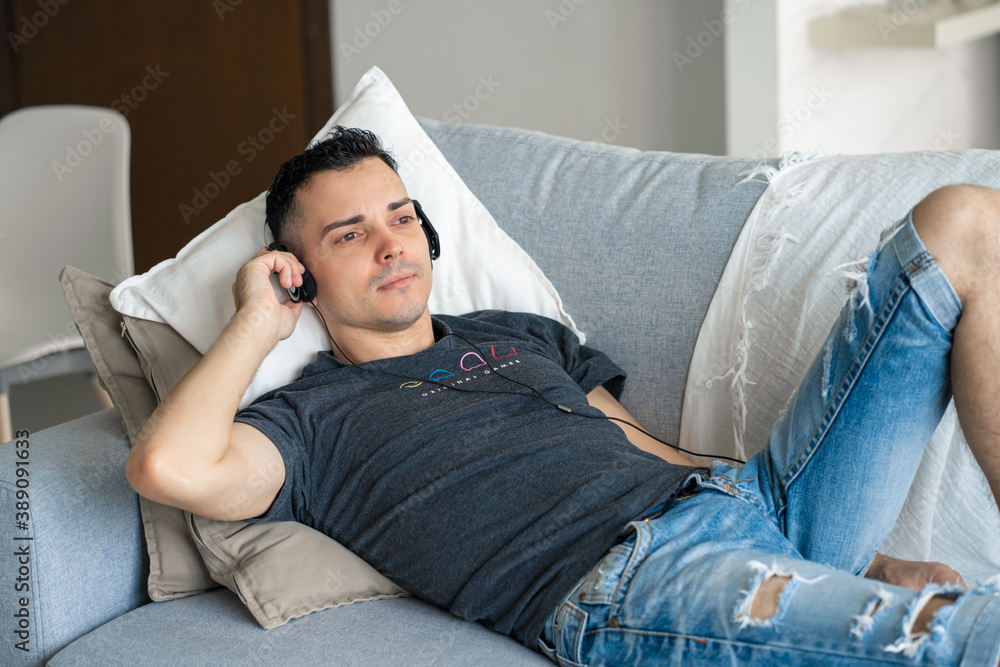 the guy enjoys the music while lying on the couch with headphones. Relaxation with music the guy enjoys the music while lying on the couch with headphones. Relaxation with music