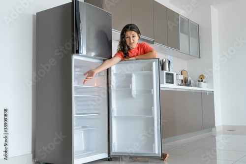 The girl is surprised at the empty refrigerator. Lack of food. Food delivery