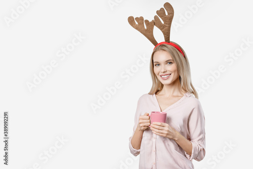 Beautiful woman wearing horns and holding cup of tea on white background