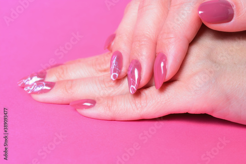 female hands with painted nails on pink background.