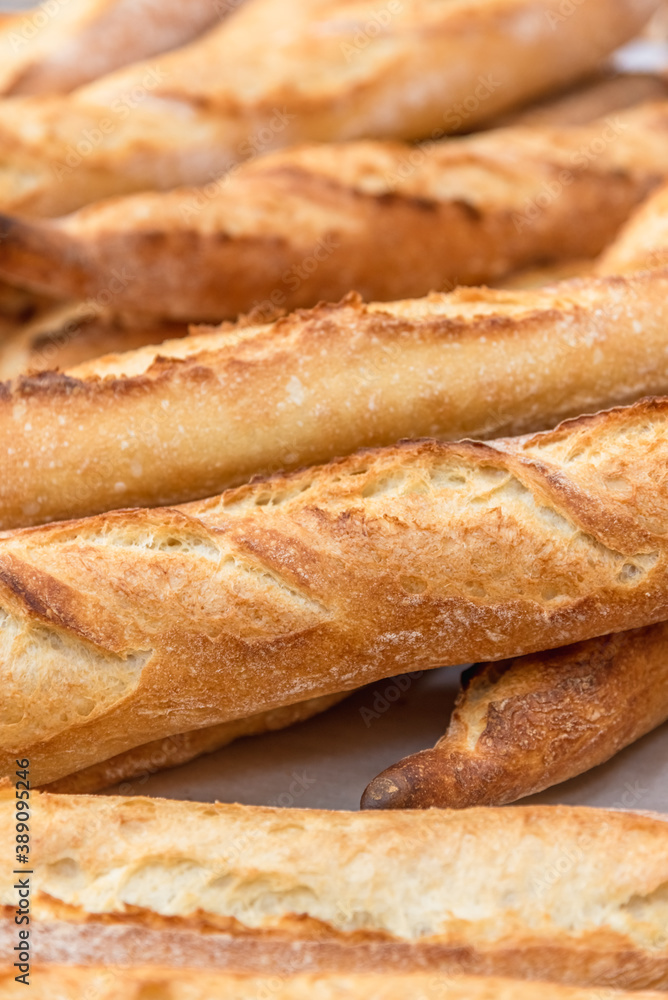 Freshly baked French baguettes lie on a light-colored surface. Rustic handicraft bread, handmade