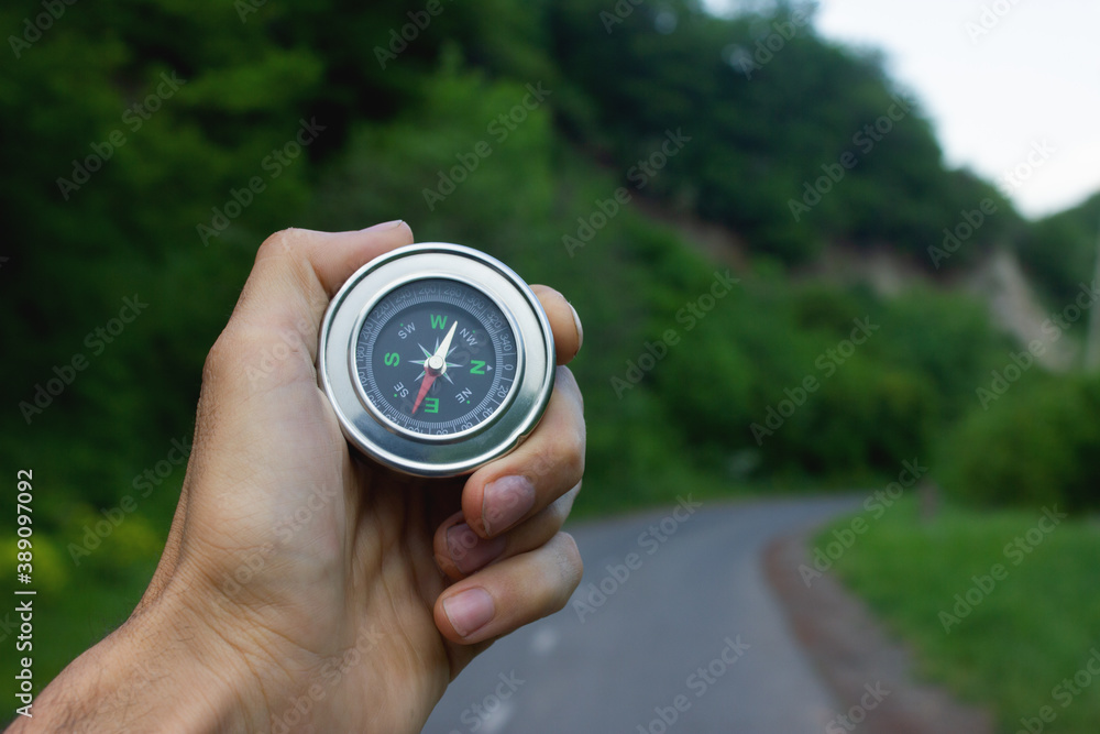 Compass in hand on a background of nature Compass in hand on a background of nature
