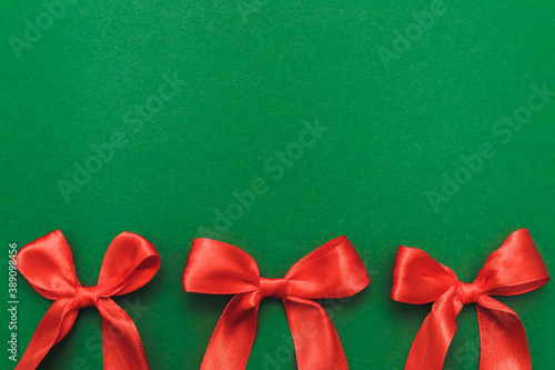 Happy new year greeting card. Christmas border with three red bows on a green background. Winter vacation. Place for text. Top view, flat lay. Christmas. Template, banner.