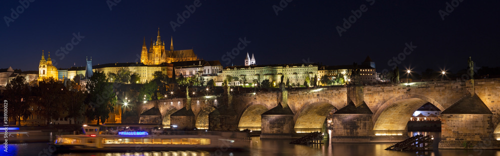 PRAGUE, CZECH REPUBLIC - OCTOBER 16, 2018: The panorama of Charles Bridge, Castle and Cathedral from promenade over the  Vltava river at dusk.