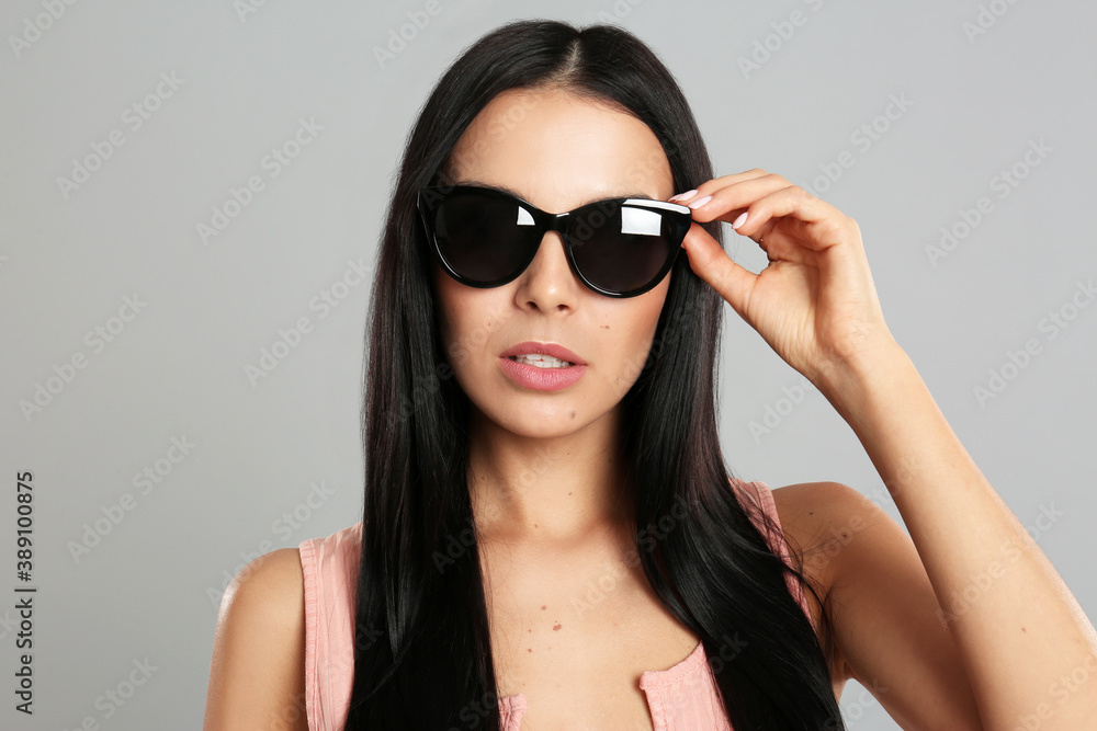 Naklejka premium Beautiful woman wearing sunglasses on grey background