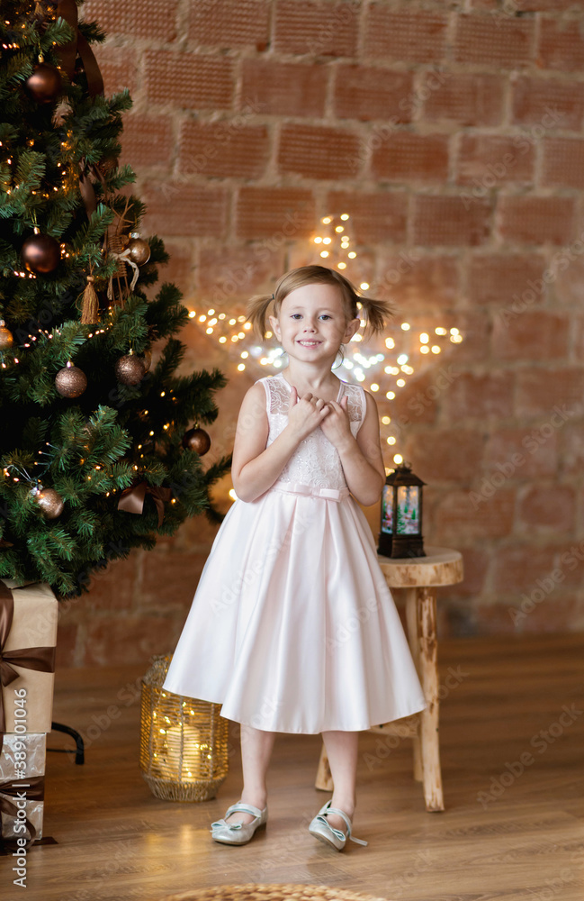 The adorable little girl in gorgeous dress standing near Christmas tree The adorable little girl in gorgeous dress standing near Christmas tree