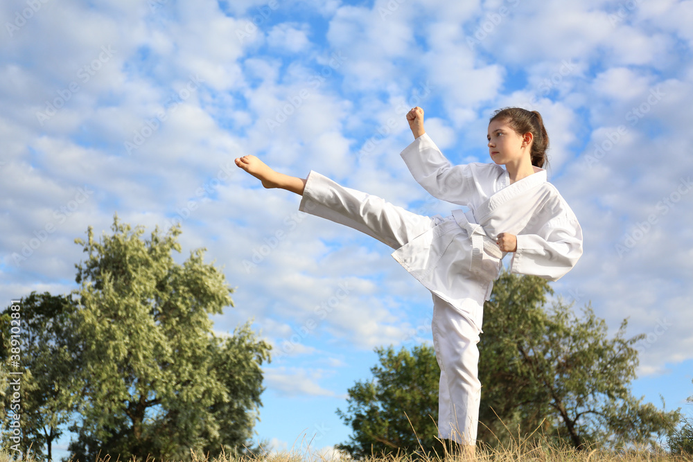 Cute little girl in kimono training karate outdoors Cute little girl in kimono training karate outdoors