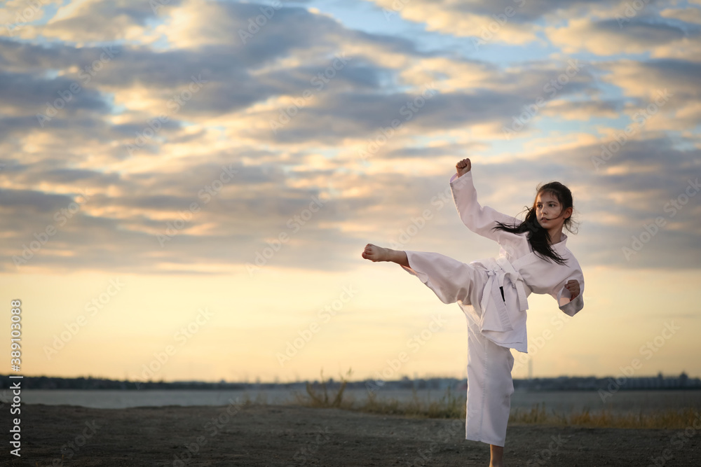 Cute little girl in kimono practicing karate outdoors Cute little girl in kimono practicing karate outdoors